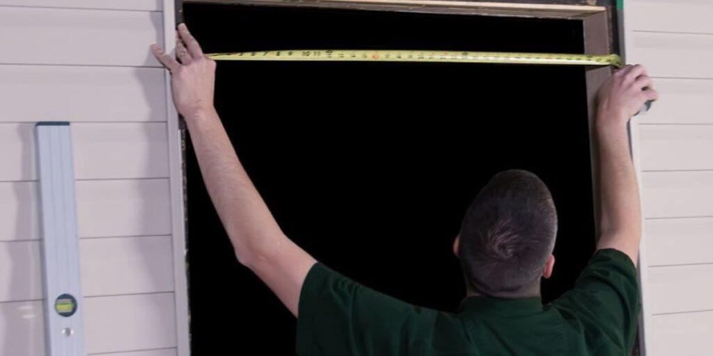 Homeowner measuring the width and height of a door frame with a tape measure to ensure accurate replacement door sizing | How to Measure a Door Frame for Replacement