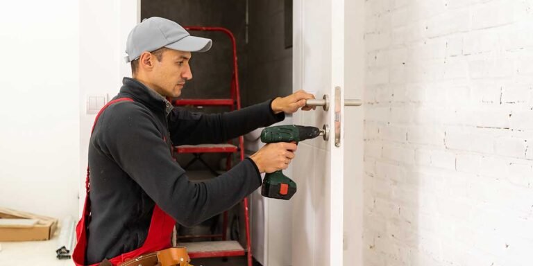 A professional technician kneels beside a white interior door and uses a cordless drill during door installation in Lawrenceville, GA.